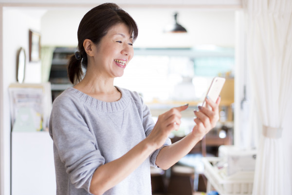 スマホを遠くで眺める高齢女性の画像